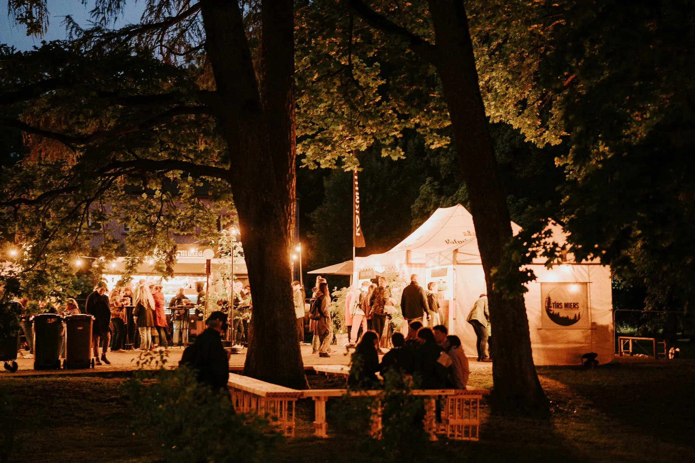 Nakts koncerts ar spožām skatuves gaismām un klausītāju siluetiem